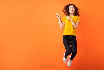 Fototapeta na wymiar Young asian girl jumping up on orange background