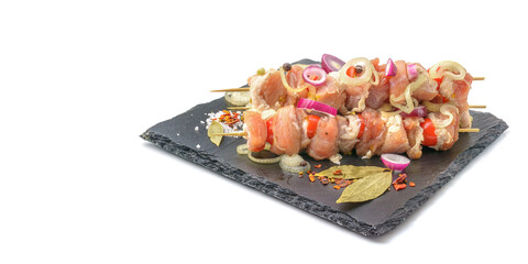 Raw pieces of pork shish kebab in marinade with pepper, onion,bay leaf.Pork kebab, ready to cook, barbecue, isolated on a white background.Selective focus.