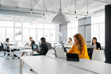 Distanced multiethnic group of people focused working on their laptops in a modern coworking