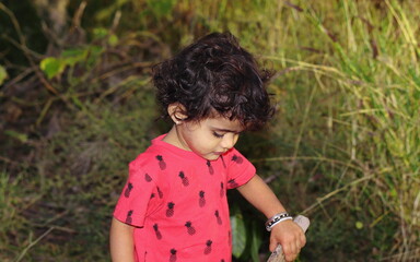 Portrait photo of a small Indian child playing with wood in the garden