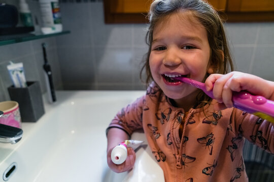Happy little girl brushing teeth in bathroom