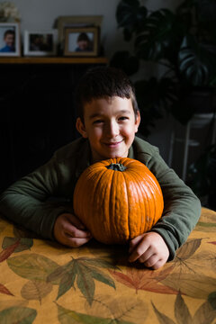 Happy kid with a pumpkin on a table