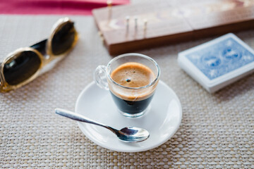 Small cup of espresso on table with cribbage board.
