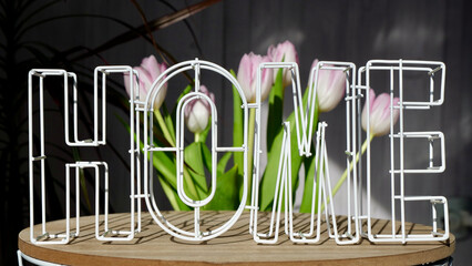 Close-up of letters at home on the background of pink flowers tulips on a sunny day. Home comfort in small trifles