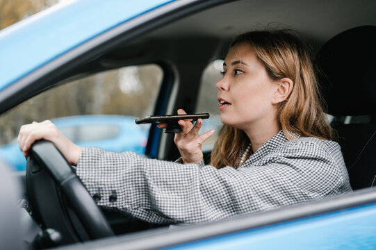 Cheerful woman recording voice message in car