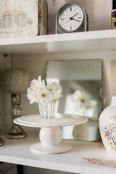 Decorative objects and flowers in glass vase on bookshelf