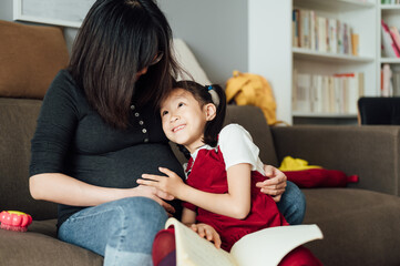 Pregnant mother and daughter at home