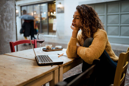 Woman in a bar, working with her laptop while drinking a glass o