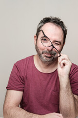 Fototapeta premium Portrait of a smiling mature man with bear wearing red t-shirt and glasses.