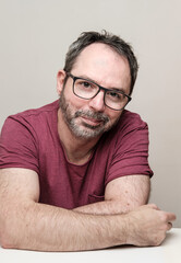 Obraz premium Portrait of a smiling mature man with bear wearing red t-shirt and glasses.
