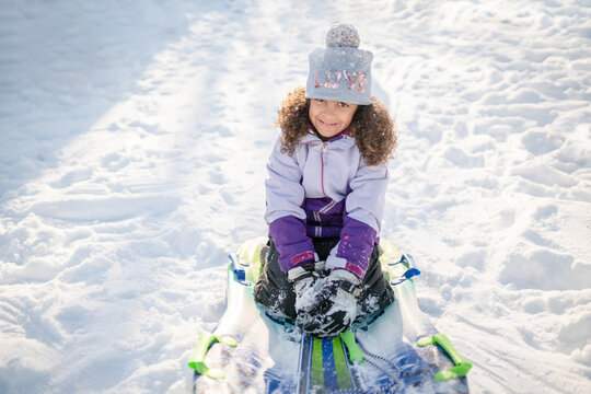 Curly haired girl on sled in snow