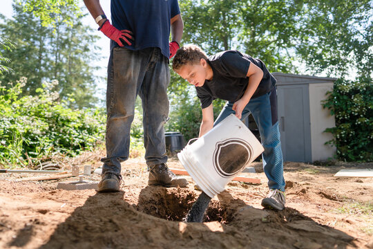 Boy pours bucket of gravel.