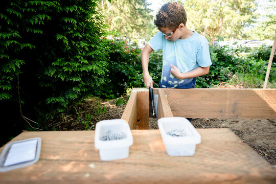 Boy hammers deck of playhouse