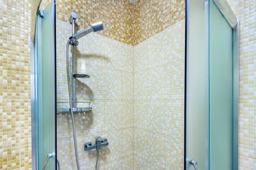 Blue glass walk-in shower cabin with open doors in corner of home bathroom