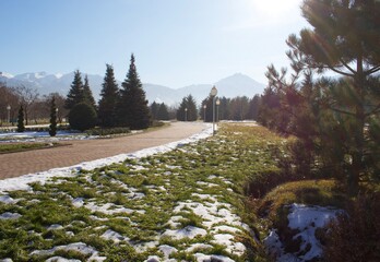 Beautiful mountains, green grass, snow, trees, blue sky. Spring. Park named after the first president, Almaty. Kazakhstan.