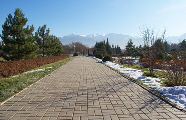 Beautiful mountains, green grass, snow, trees, blue sky. Spring. Park named after the first president, Almaty. Kazakhstan.