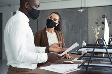 Multiracial colleagues in medicals masks discussing papers