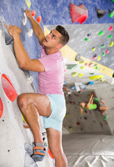 Sporty man training at bouldering gym without special climbing equipment..