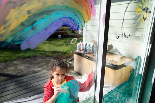 Girl paints vibrant mural on window
