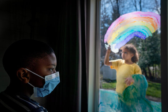 Boy in mask watches girl paint mural - Powered by Adobe