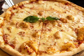 Pizza Margherita with mozzarella and basil leaves on wooden stend. Traditional italian food