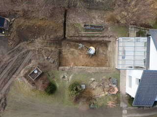 Drones aerial view of a construction site of a pool, small yellow excavator digs hole for pool and...