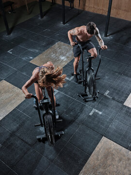 Two athletes with air bikes in the gym