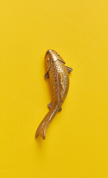 Golden fish from metal on a yellow background.
