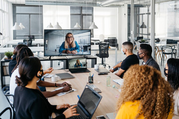 Multiehtnic group wearing face masks having a business virtual meeting