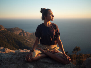 Young woman meditate on the rock