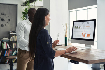 Contemporary workers checking statistics of company on computer