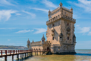 Scenic Belem Tower and wooden bridge miroring with low tides on Tagus River. Torre de Belem is...