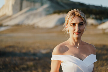 Fototapeta na wymiar Portrait of a beautiful blonde bride in a white dress with bare shoulders