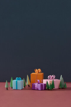 Decorative christmas paper tree with several present gifts boxes on color background.