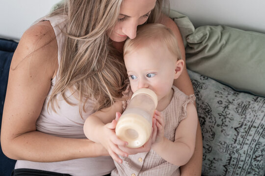 Woman sits while toddler drinks bottle