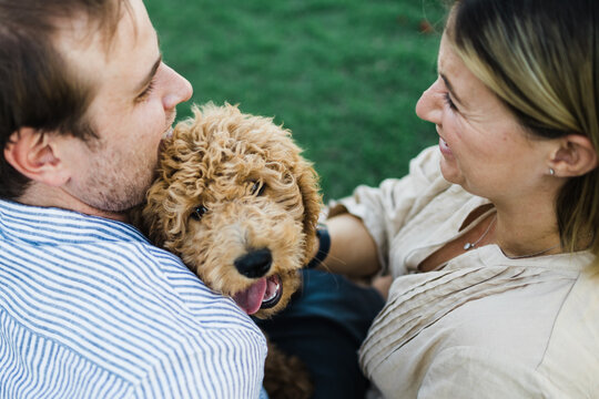 Couple cuddle and hold their puppy