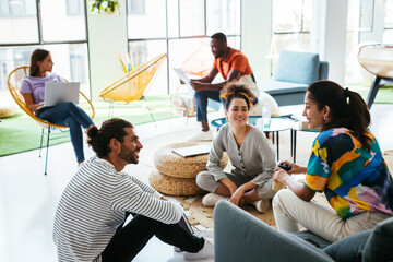 Friendly diverse colleagues talking in creative workplace