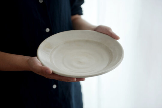 Holding a homemade stoneware dish in a Japanese-style home environment