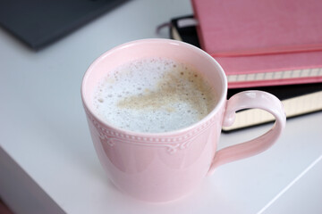 Pink mug with coffee on white desk