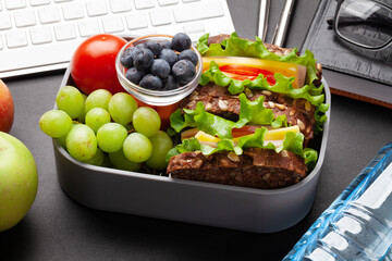 Healthy office lunch box with sandwich and fresh vegetables