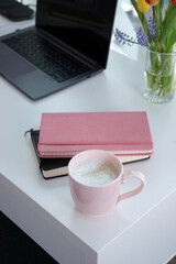 Pink mug with coffee on white desk