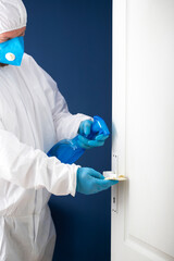 Coronavirus COVID-19 prevention. Man wiping doorknob with antibacterial disinfecting wipe for killing coronavirus.