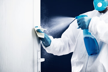 Coronavirus COVID-19 prevention. Man wiping doorknob with antibacterial disinfecting wipe for...