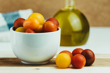 Closeup of various types of cherry tomatoes in a white bowl on a wooden table