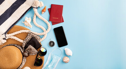 Flat lay travelling objects with summer hat, smartphone, passport, sunglasses and compass on blue background