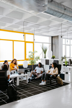 Group of diverse coworkers having a relaxed conversation during coffee break in a modern work place