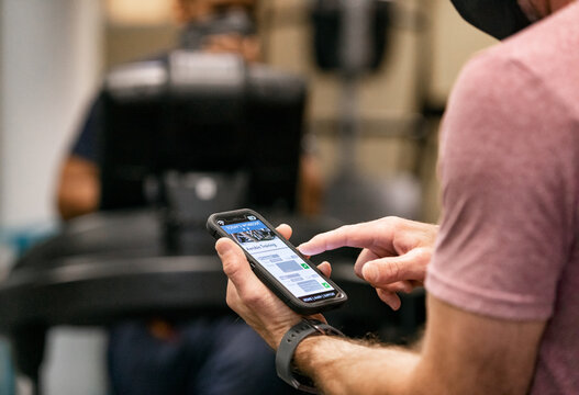 Gym: Man With Face Mask Using Aerobic Tracking App On Phone