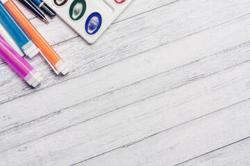 watercolor paint markers and pencils on a wooden table top view Copy Space