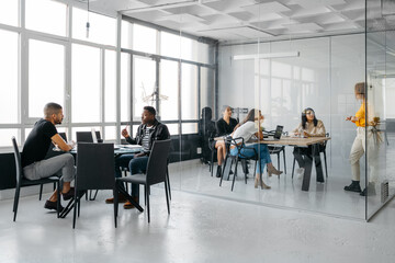 Women having a meeting while two men are having a conversation outside ni a modern office