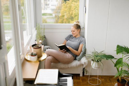 Young woman reading a book in a cozy living room